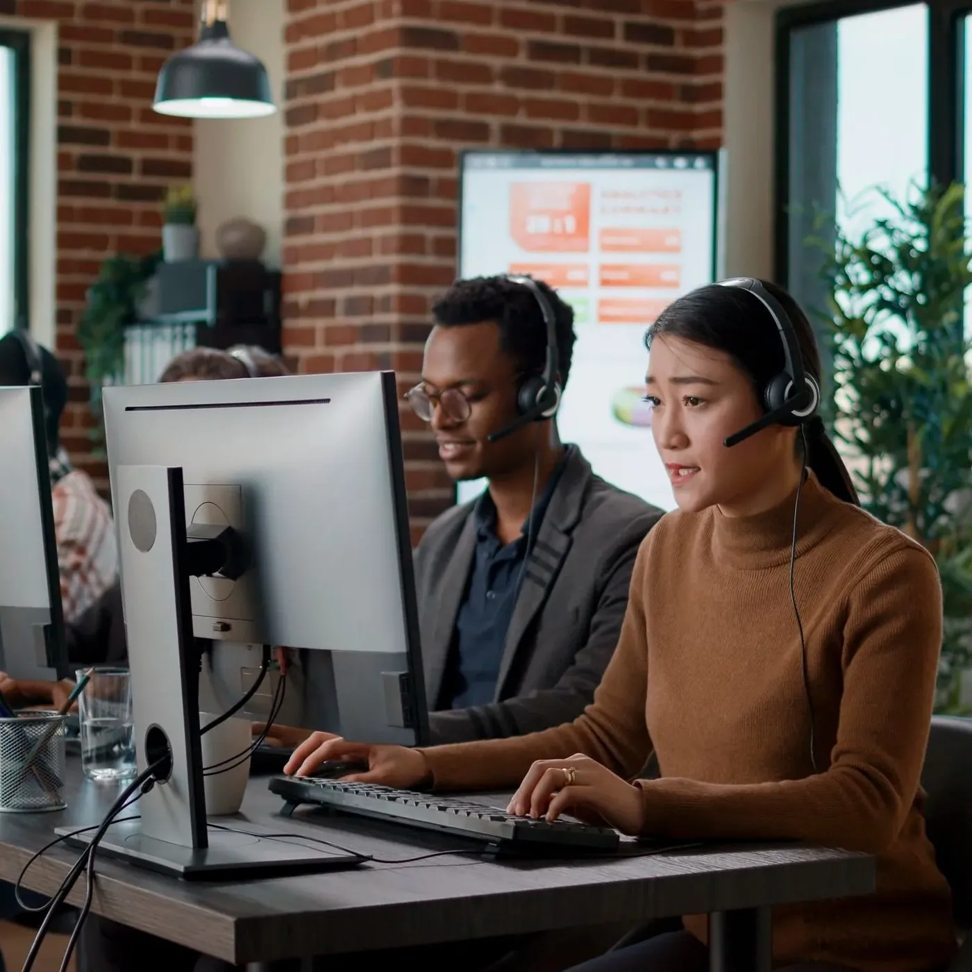 multiethnic team people working call center office using audio headset telecommunications help clients people answering call phone helpline giving assistance workstation